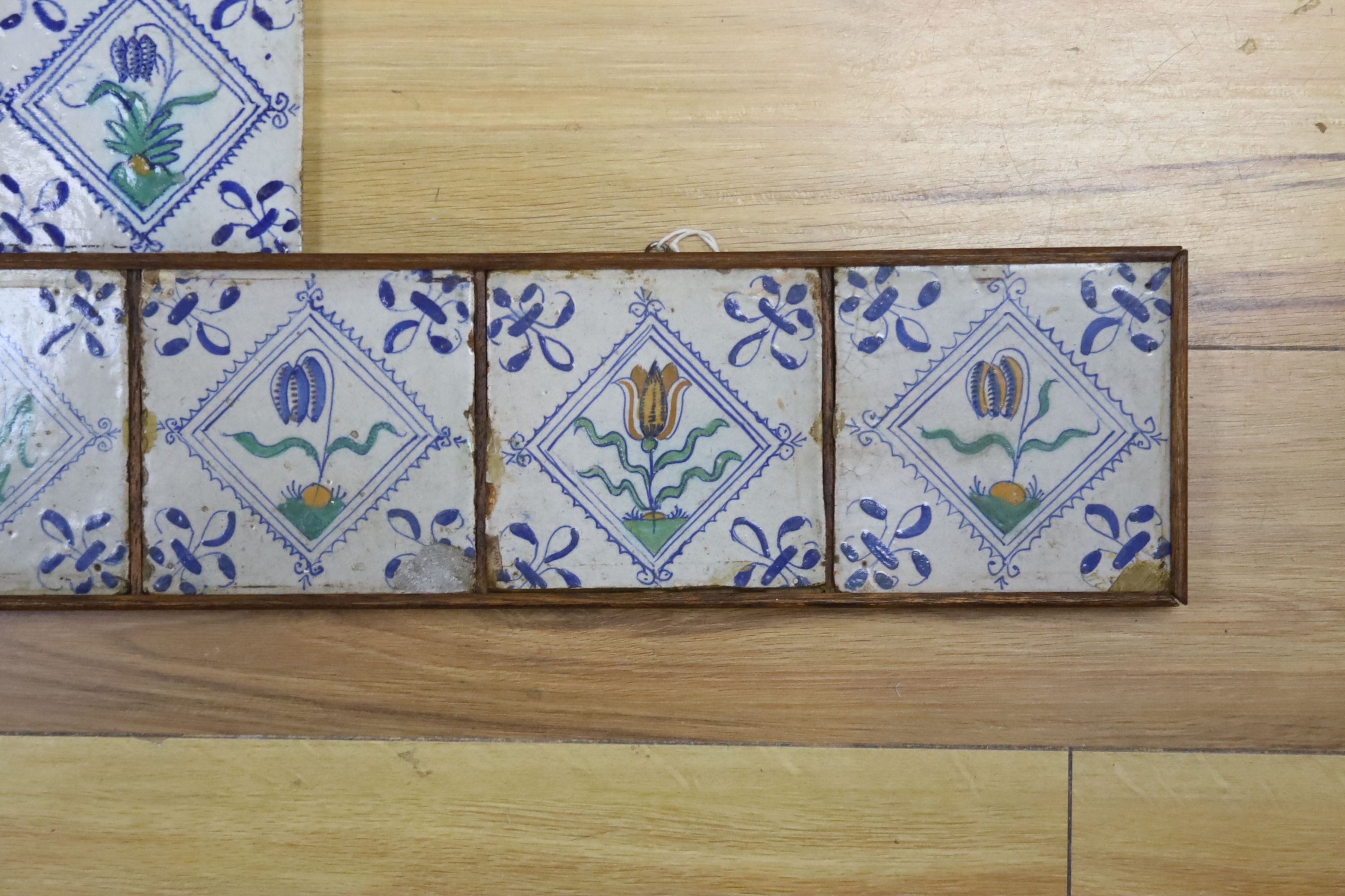 Seven 17th century Dutch Delft tiles, polychrome-decorated with tulips and having fleur-de-lys corners (framed 95cm)